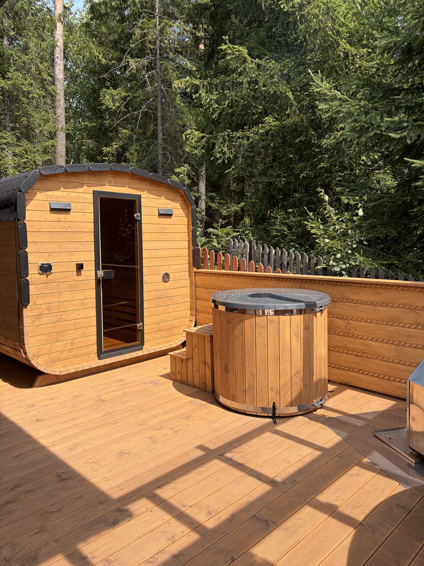 Sauna i balia z zimną wodą na tarasie pod świerkami
