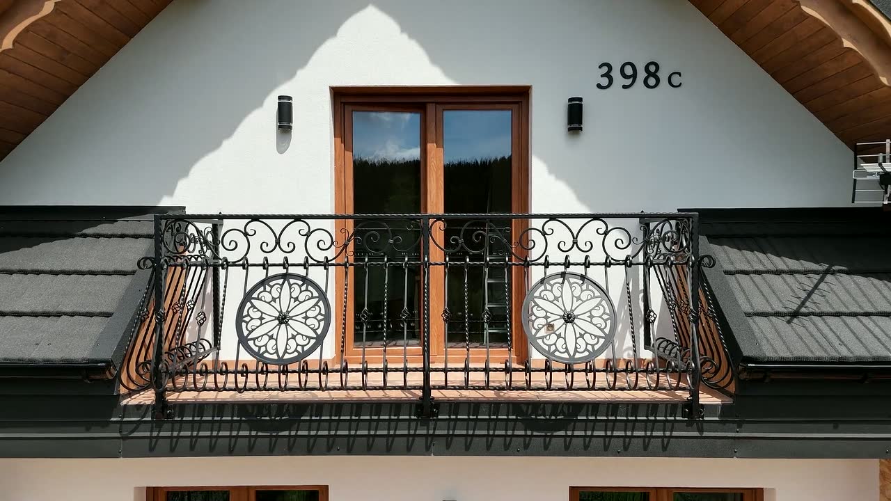 Balkon z kutą balustradą na frontowej ścianie domku